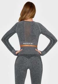 Gray long-sleeve athletic top with mesh panel and matching high-waisted leggings. Features textured fabric and "SQUATPROOF" logo.