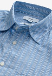 Light blue striped shirt with a relaxed fit. Features a button-down collar and white buttons. Made from smooth cotton fabric.