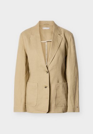 Bézs színű vászon blézer kitűnő hajtókával, két gombbal, két elöl található zsebbel és hosszú ujjakkal, egyszerű fehér háttér előtt.