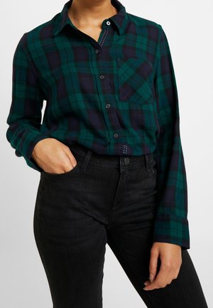 Grøn- og navyternet skjorte med knap, krave, lange ærmer og en brystlomme. Kombineret med sorte denimjeans. Tekstureret stof.