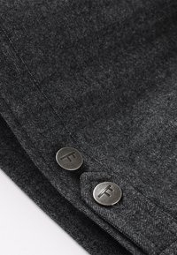 Tela de espiga gris con dos botones metálicos que presentan un logo elevado. La textura es suave y la tela tiene un brillo sutil.