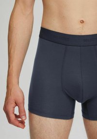 Tummanharmaat boxerit, jotka on valmistettu joustavasta kankaasta. Ominaisuuksiin kuuluu pehmeä joustovyötärö, jossa on "SELECTED"-brändäys, sekä istuva leikkaus.