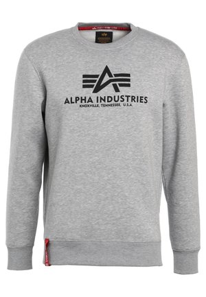 Hanorac gri cu mâneci lungi, decolteu rotund, având un logo negru "ALPHA INDUSTRIES" și o etichetă roșie pe cusătura laterală.