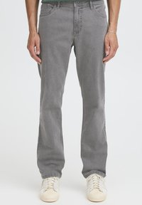 Jeans di denim grigio con vestibilità a gamba dritta, design a cinque tasche e sfumature discrete. Abbinati a sneakers color avorio.