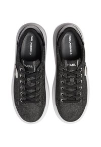 Czarne sneakersy z teksturowanym wierzchem z tkaniny z błyszczącym wykończeniem, białymi gumowymi podeszwami i czarnymi sznurowadłami. Logo widoczne na języku.