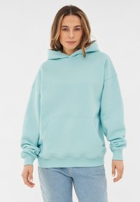 Felpa oversized azzurro chiaro realizzata in tessuto morbido, con tasca a marsupio, polsini a costine e orlo arrotondato.