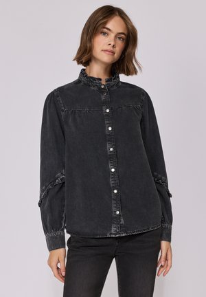 Chemise en denim noir avec un col ondulé, fermeture à bouton et manches froncées avec éléments ajustables. Texture douce avec un fini délavé.