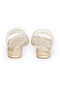 Złote sandały na płaskiej podeszwie z regulowanym paskiem wokół kostki i metalową klamrą, ozdobione błyszczącymi akcentami i teksturowanym wykończeniem.