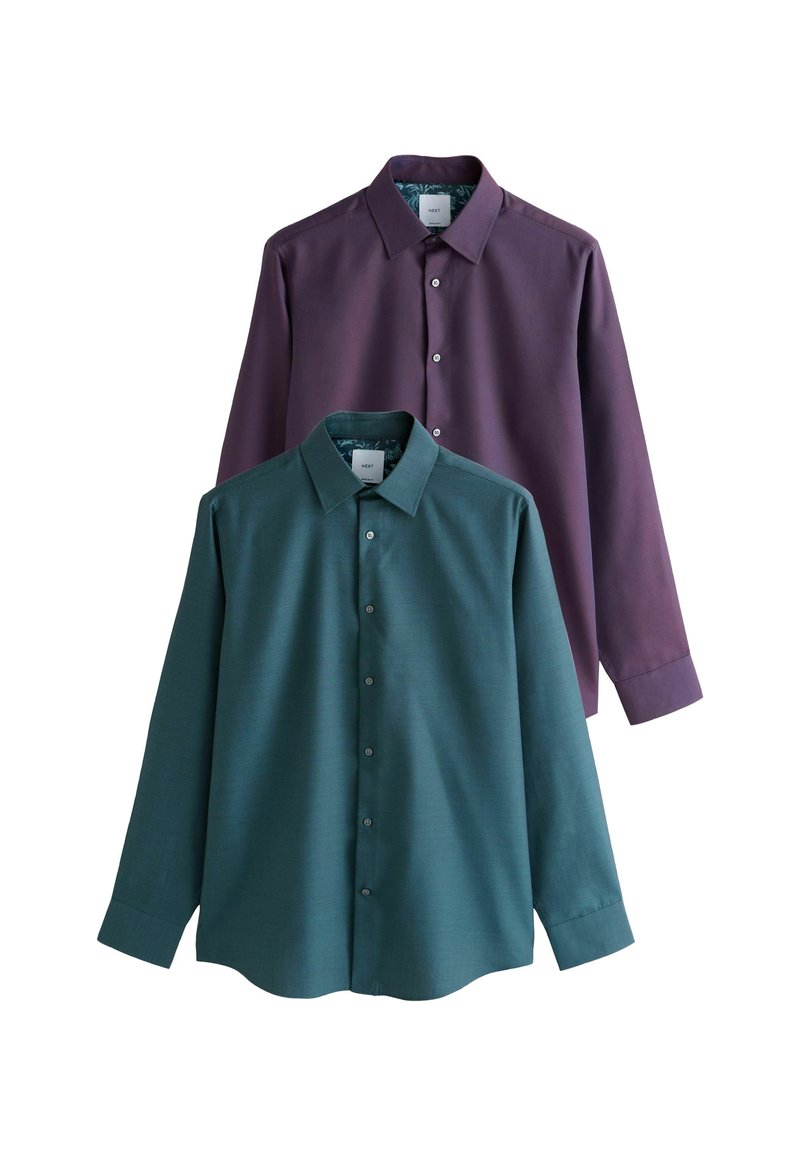 Koszulki z kołnierzykiem, jedna w odcieniu teal, a druga fioletowa, mają długie rękawy, przednią zapięcie na guziki i gładką fakturę materiału. Metki widoczne wewnątrz kołnierzyków.