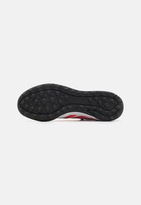 Suela de zapato de goma negra con pequeños agarres circulares, con un diseño elegante, acentos rojos y patrones estriados para tracción.