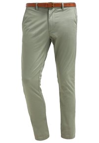 Ljusgröna byxor gjorda av slät tyg, med smal passform, framfickor och ett brunt läderbälte med ett guldspänne.