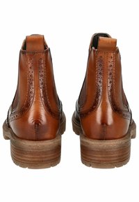 Braune Lederstiefeletten mit Brogue-Verzierungen, runder Zehenpartie, elastischen seitlichen Einsätzen und gestapeltem Holzabsatz. Glatte Oberfläche und strukturierte Akzente.