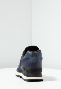 Marineblaue Sneaker mit einem strukturierten Obermaterial aus Leder, schwarzen Akzenten, gepolstertem Kragen und einer weißen Zwischensohle mit einer gemusterten Außensohle.