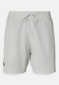 Un short de sport gris clair en maille, avec une taille élastique et un cordon de serrage, ainsi qu'un petit logo noir sur le bas à gauche.