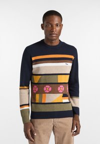 Maglione lavorato a maglia con scollo rotondo, caratterizzato da audaci motivi geometrici in blu navy, arancione, marrone, giallo e rosa. Polsini e orlo a coste.