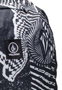 Mustavalkoinen kuviollinen reppu, jossa on sekoitus raitoja ja geometrisia muotoiluja. Sisältää Volcom-logotagin. Kestävä kangas.