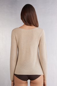 Beige långärmad tröja med rundad halsringning, tillverkad av mjukt material, med en avslappnad passform och slät yta i en enhetlig färg.