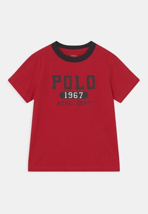 Rød t-shirt med korte ærmer, sort krave og teksten "POLO 1967 ATHL. DEPT." trykt i sort og hvid på forsiden.