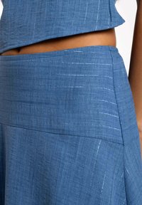 Conjunto de dos piezas en azul denim que presenta una tela texturizada y tejida con sutiles rayas brillantes, top corto y diseño de falda de cintura alta.