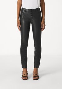 Must have mustade nahkstooted, mis on slim fit stiilis, esikottide ja nupuga kinni tõmbamisega. Sile tekstuur ja pahkluu pikkusega disain.