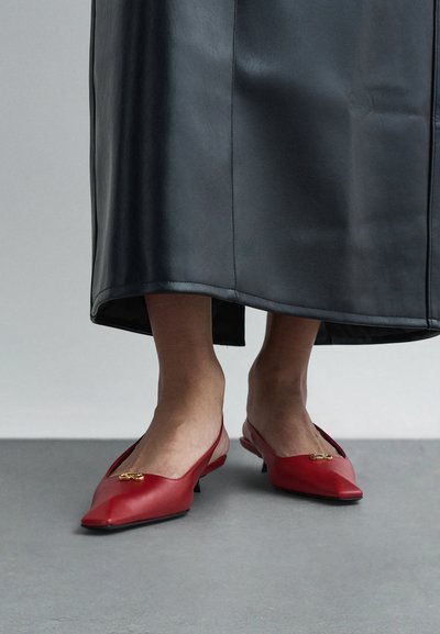 Red leather shoes with a pointed toe and low heel, featuring a gold accent on the vamp and an open back design.