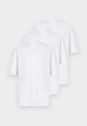 Dwie osoby stoją obok siebie, ubrane w białe, oversize koszulki, szerokie szare spodnie i czarne buty na jednolitym białym tle.