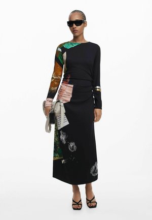 Abito nero a maniche lunghe con stampe miste, motivi floreali e design asimmetrico. Abbinato a una borsa leggera e occhiali da sole.