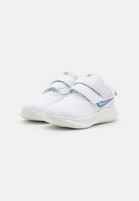 Zapatillas deportivas blancas con parte superior de malla, correas de Velcro ajustables y un detalle de swoosh azul. Presenta una suela de goma blanca texturizada.