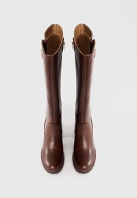 Bottes montantes en cuir marron avec une texture lisse, des fermetures éclair sur le côté et un design à bout arrondi. Intérieur doublé d'un matériau beige contrastant.