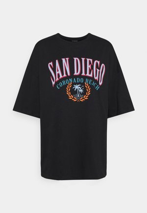 Black T-shirt with "SAN DIEGO" in large pink and white letters, "CORONADO BEACH" in blue below, and palm tree and laurel graphic in orange and blue.