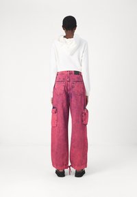 Pantalons cargo rose vif avec une coupe décontractée, dotés de grandes poches latérales, d'un ourlet à cordon de serrage et d'une taille haute. Matière en denim texturé.