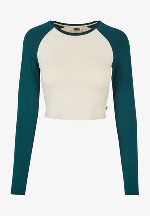 Top corto con maniche lunghe. Presenta un corpo crema e maniche teal. Realizzato in morbido cotone, con scollatura a girocollo e dettagli di cucitura minimi.