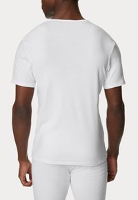 Camiseta blanca de cuello redondo hecha de algodón, con mangas cortas y un corte regular, mostrada desde la parte posterior con una textura suave.