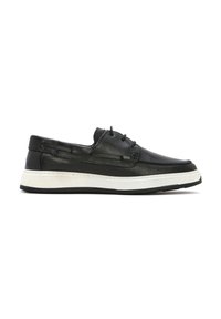 Scarpe da barca in pelle nera con suola in gomma bianca, dotate di una parte superiore texture e lacci decorativi sui lati. Design piatto e casual.