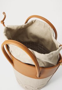 Borsa a secchiello con corpo in tela beige e dettagli in pelle marrone. Presenta una chiusura a coulisse e un interno a fantasia. Due manici robusti.