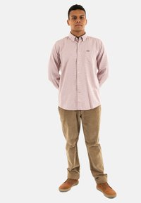 Lichtroze geruite blouse met lange mouwen, borstzak, gecombineerd met tan corduroy broek en bruine schoenen.