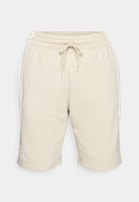 Beige sweatshorts med elastisk midje och dragsnöre. Sidelommer og en hvit logo på venstre kant. Laget av mykt materiale.
