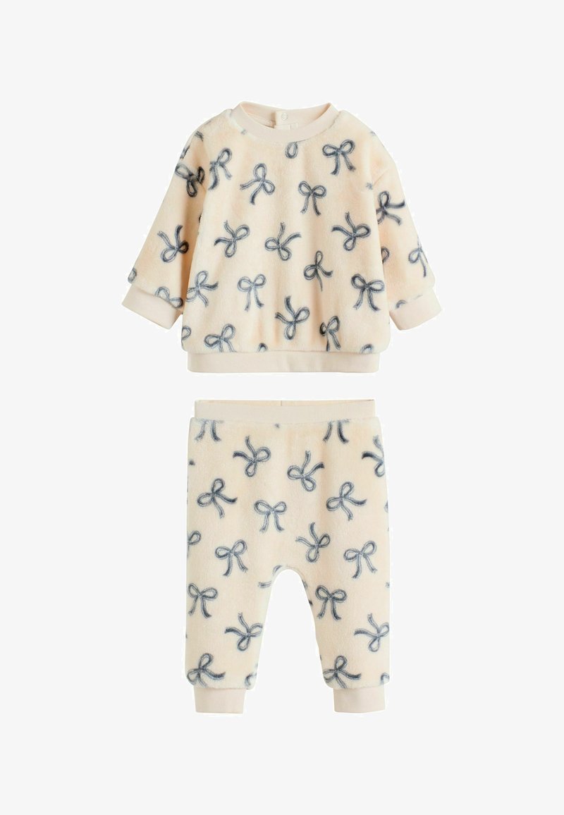 Fleece two-piece set featuring a crew-neck top and elastic waist pants. Pale peach with navy bow prints and ribbed cuffs. Soft texture.