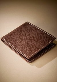 Braune Lederbörse mit strukturiertem Oberfläche, weißen Nähten, gefaltetem Design und abgerundeten Kanten. Kompakte und praktische Form.