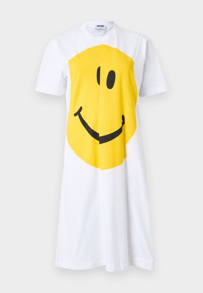 Robe blanche à manches courtes avec un grand motif visage souriant jaune centré sur le devant, col rond et étiquette Moschino à l'intérieur du col.