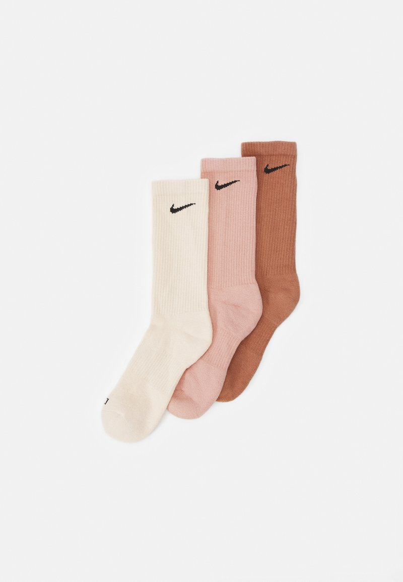 Set di tre calzini in avorio, rosa e marrone. Texture a coste con logo Nike nero su ciascuno. Lunghezza classica da crew. Realizzati in materiale morbido.