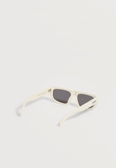 Lunettes de soleil rectangulaires blanches avec des verres foncés, inclinées montrant la monture intérieure et "Angels" imprimé sur la branche extérieure.