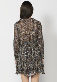 Blumenmusterkleid mit langen Ärmeln, tailliertem Schnitt, geschichtetem Rüschensaum und einem halbtransparenten schwarzen Stoff mit orangefarbenen, gelben und lila Akzenten.