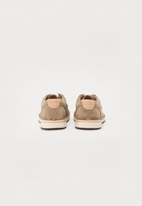 Scarpe in suede taupe con punta arrotondata, linguetta sul retro e suola in gomma beige. Dettagli cuciti lungo i bordi. Design minimalista.