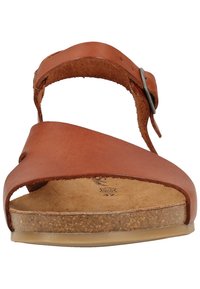 Sandal in pelle marrone con punta aperta, cinturino largo e fibbia regolabile; plantare in sughero testurizzato e suola in gomma per una buona aderenza.