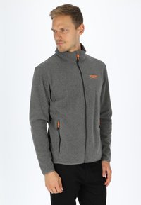 Gray fleece jacket with high collar, front zipper, and orange accents; features two side pockets with zippers and textured fabric.