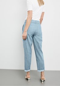 Ljusblå denimbyxor med en avslappnad passform, uppvikta fållar och bakfickor. Matchad med en vit åtsittande skjorta och ljusa klackar.