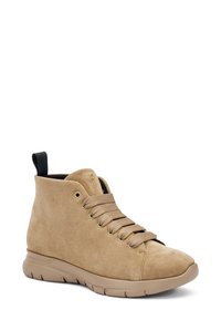 Zapato de alta con empeine de ante color beige, punta redonda, cordones planos y suela acolchada. Presenta una lengüeta en la parte trasera y un logotipo sutil en el costado.