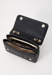 Schwarze gesteppte Handtasche aus Leder mit geräumigem Innenraum, ausgestattet mit goldfarbener Hardware und einem glatten Futter. Verschluss mit Druckknöpfen.