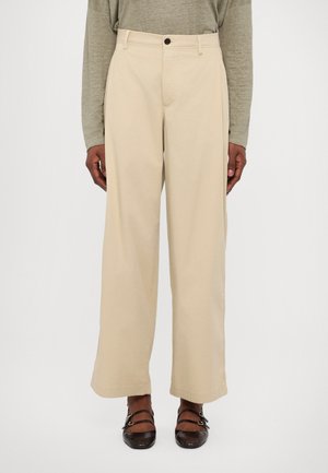 Pantalons beiges à jambes larges en coton, dotés d'une fermeture à un bouton et de poches latérales, avec une texture lisse et une coupe droite.